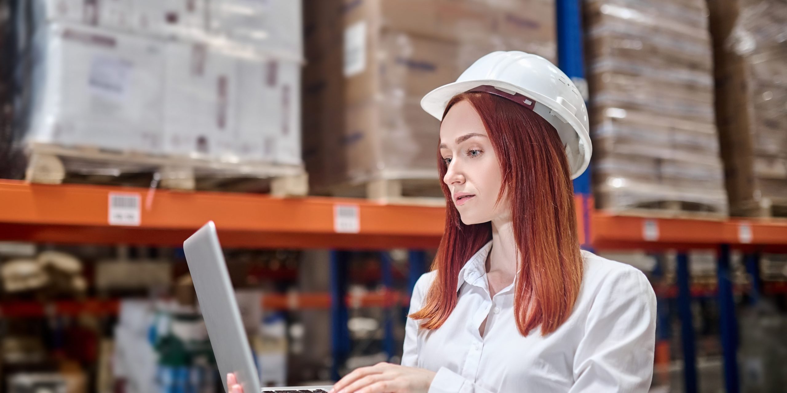 Woman in helmet holding open laptop working Custom ERP Vs SaaS ERP
